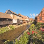 a river running through a village next to tall buildings