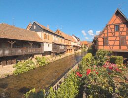 a river running through a village next to tall buildings