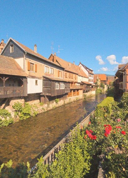 a river running through a village next to tall buildings