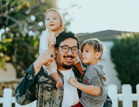 man in white shirt carrying girl in gray shirt