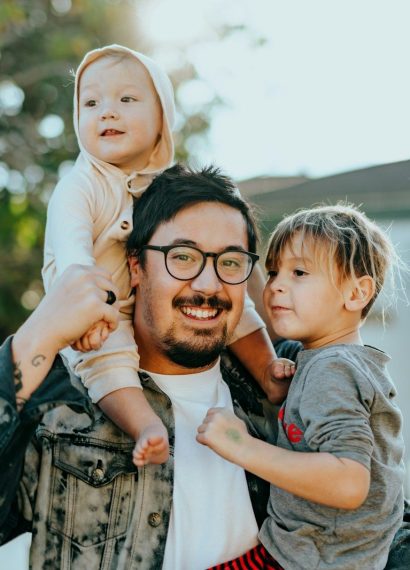 man in white shirt carrying girl in gray shirt