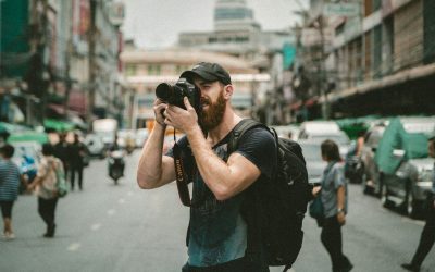 shallow focus photography of man using a DSLR camera