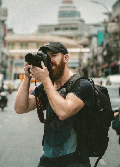 shallow focus photography of man using a DSLR camera