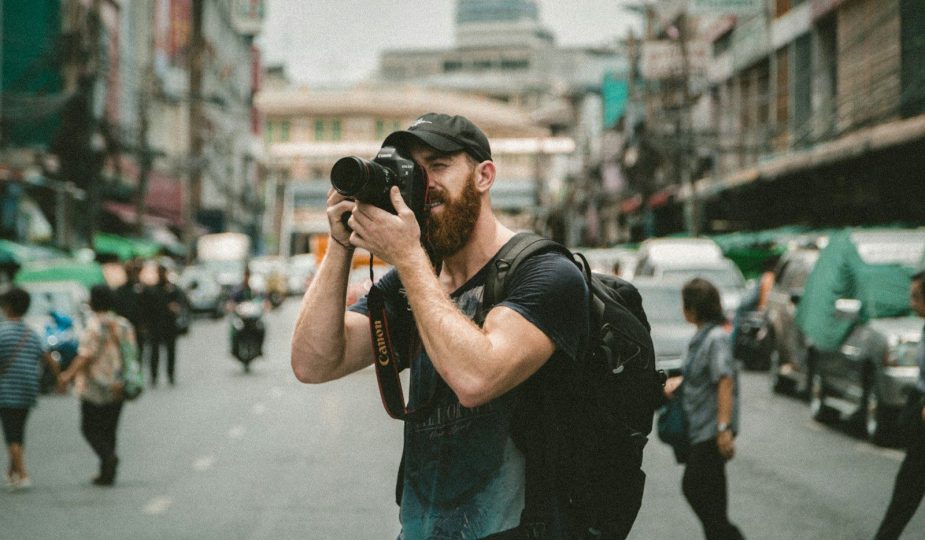 shallow focus photography of man using a DSLR camera