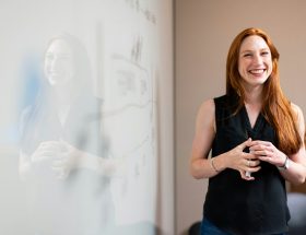 woman in blue tank top standing beside white wall