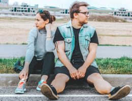 woman looking at her right sitting at curb beside man looking at his left