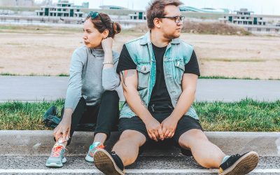woman looking at her right sitting at curb beside man looking at his left