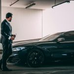a man in a suit standing next to a car