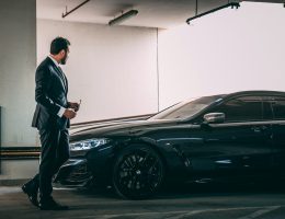 a man in a suit standing next to a car