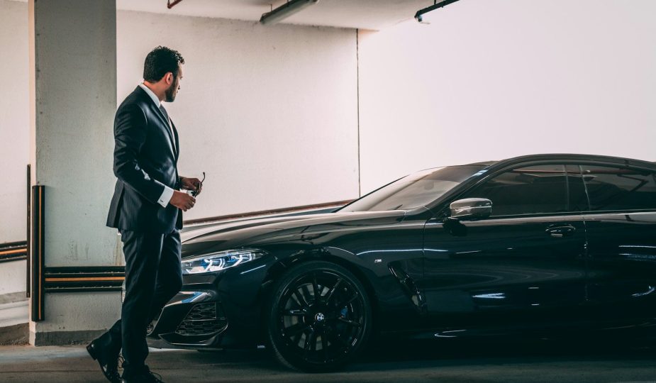 a man in a suit standing next to a car