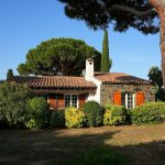 a house with red shutters and a tree in front of it